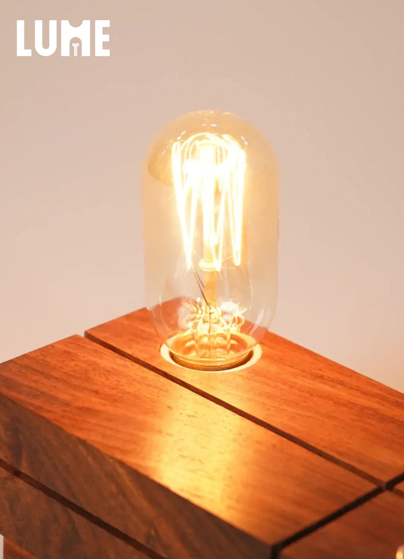 LUME solid wood table lamp with exposed Edison bulb casting warm amber glow on a wooden surface