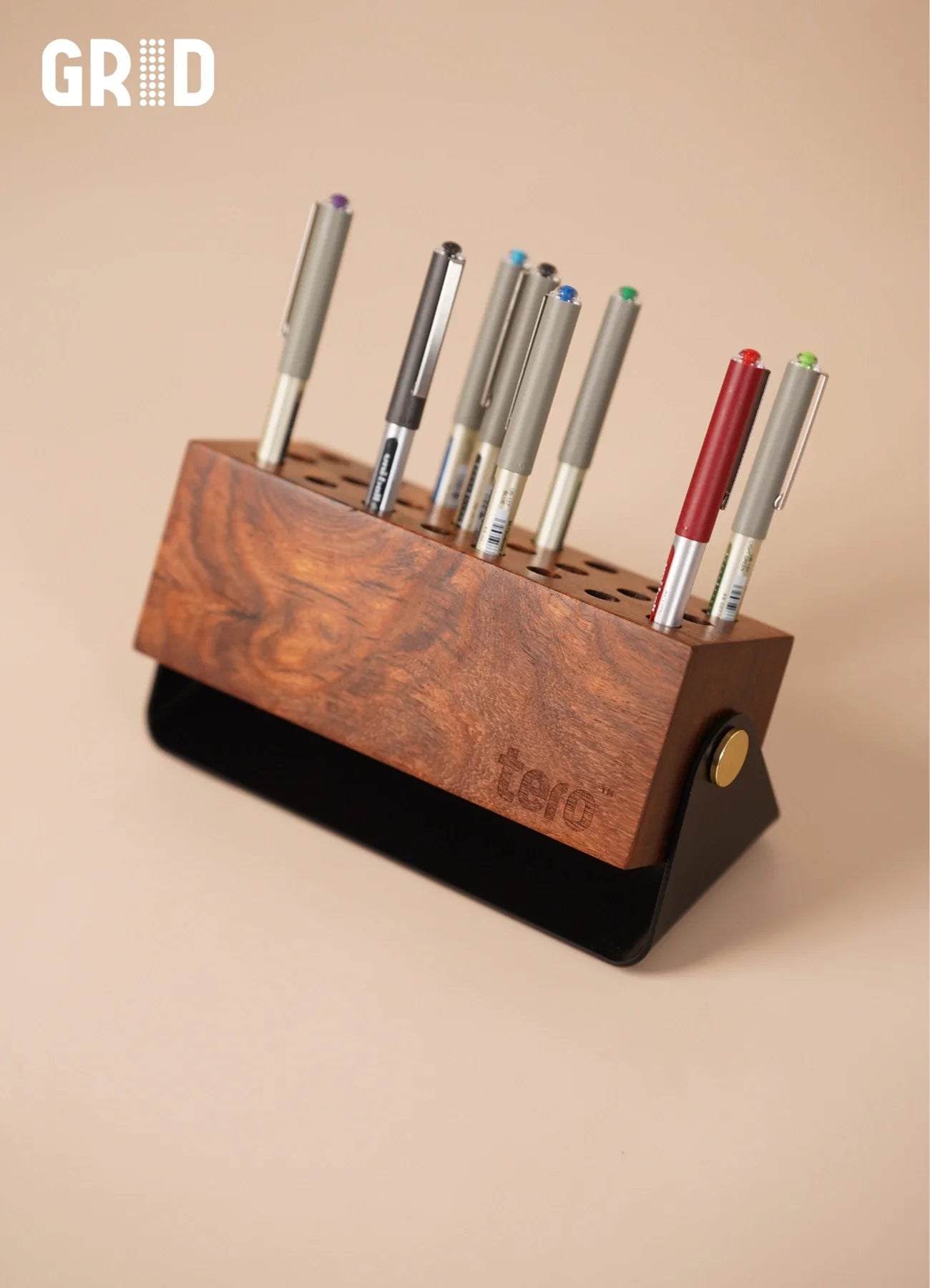 GRID solid wood pen holder in use with pens and markers in 24 precision slots on a workspace